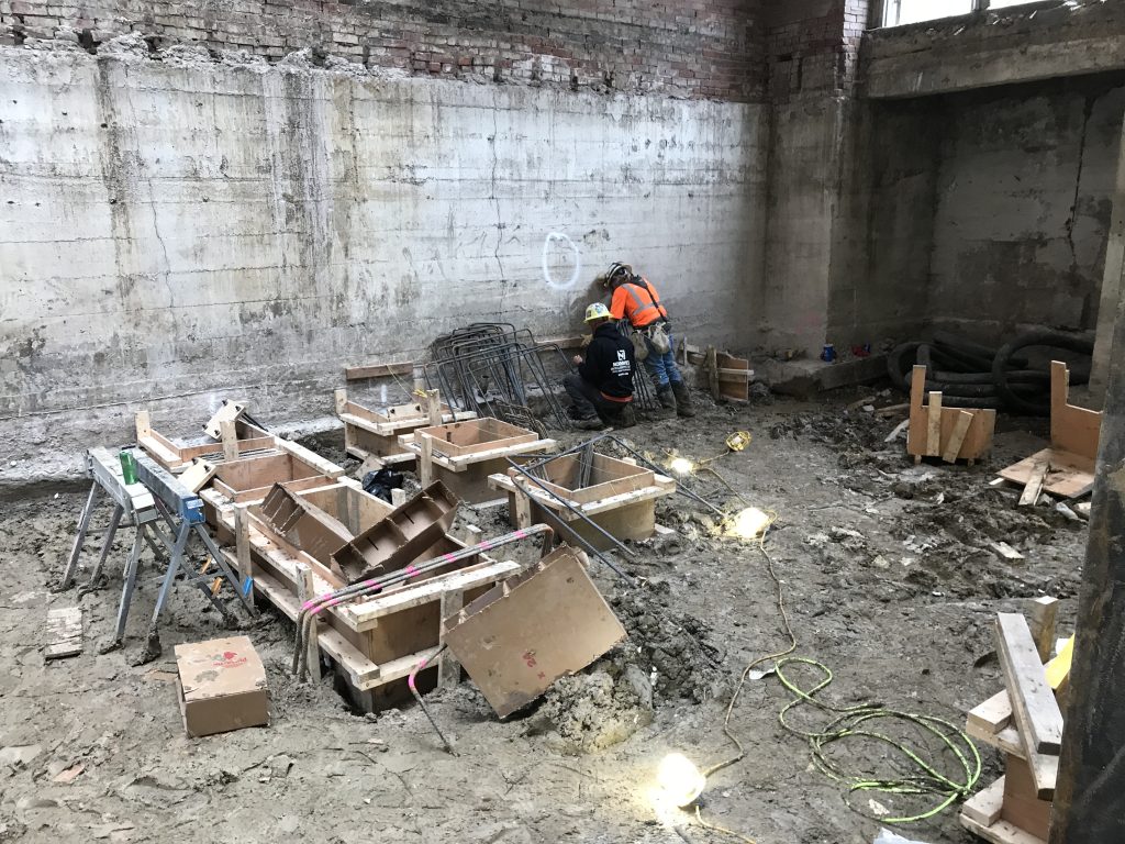 Construction workers installing helical peirs